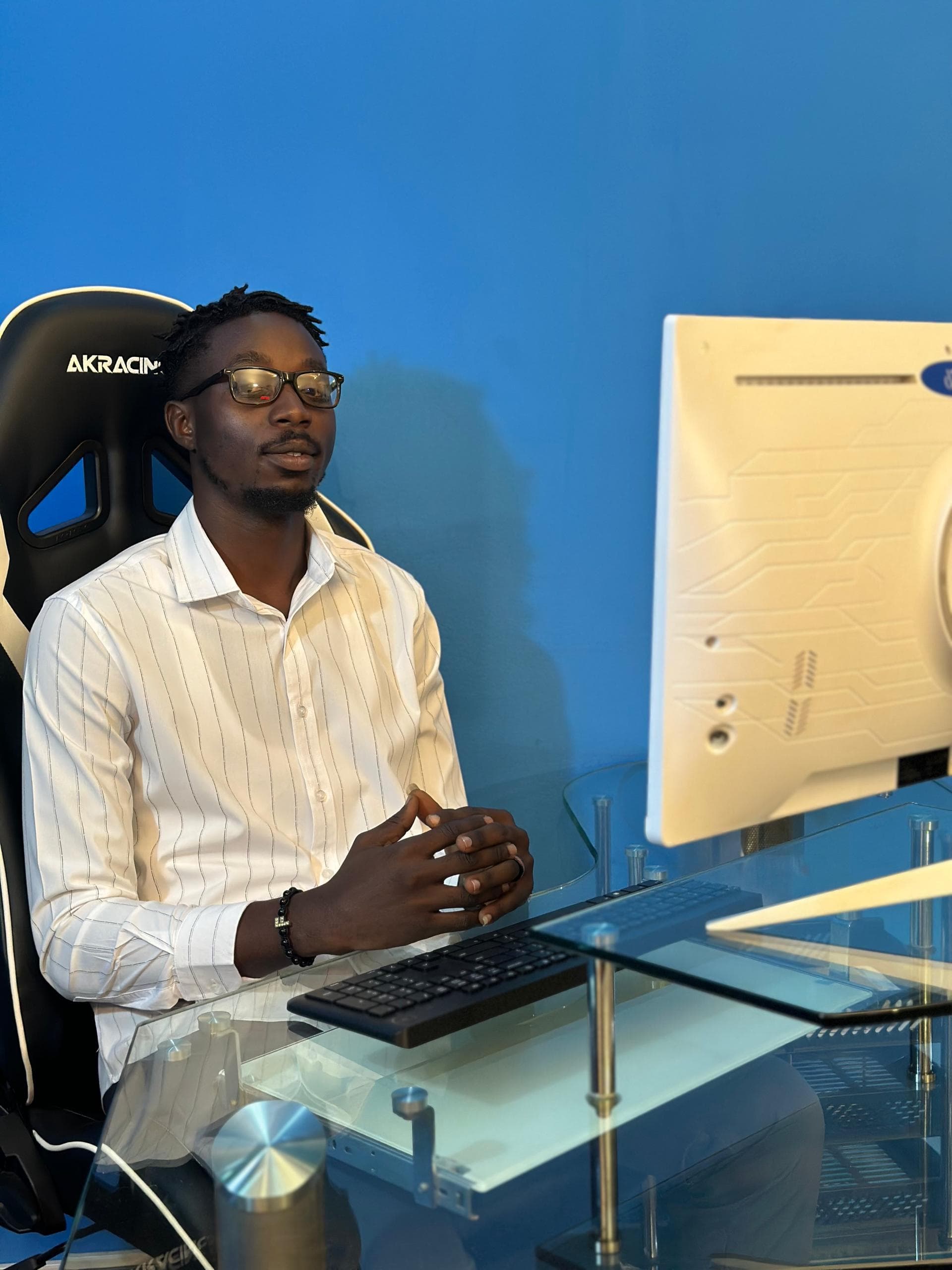 Team member seated at a glass desk beside a monitor