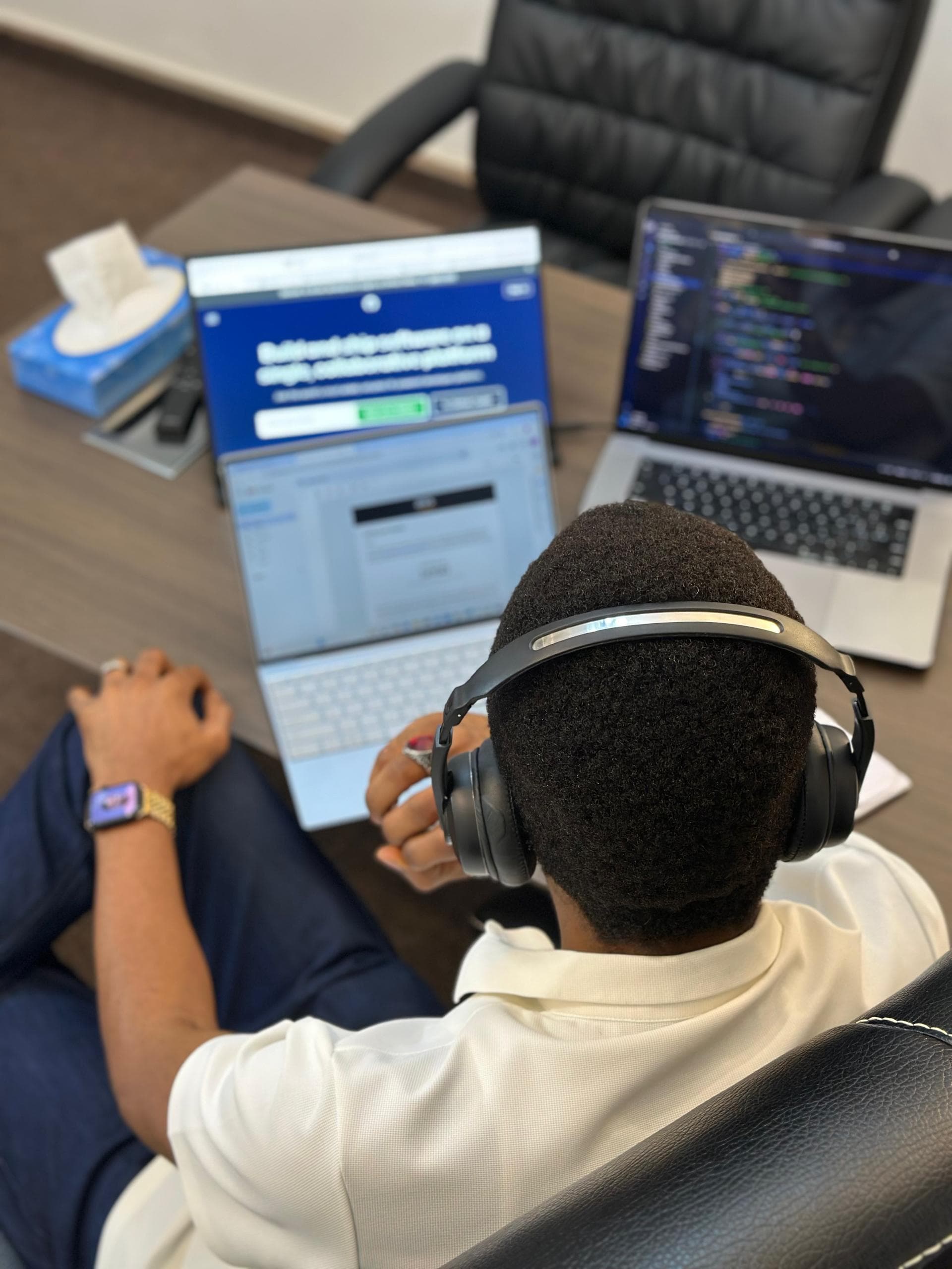 Developer in headphones working across two laptops