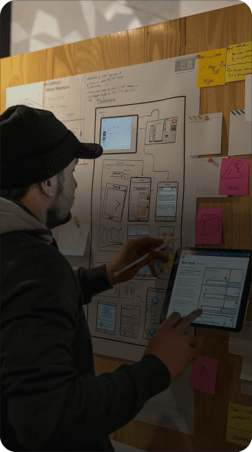 Designer sketching interface layouts on a wall of paper