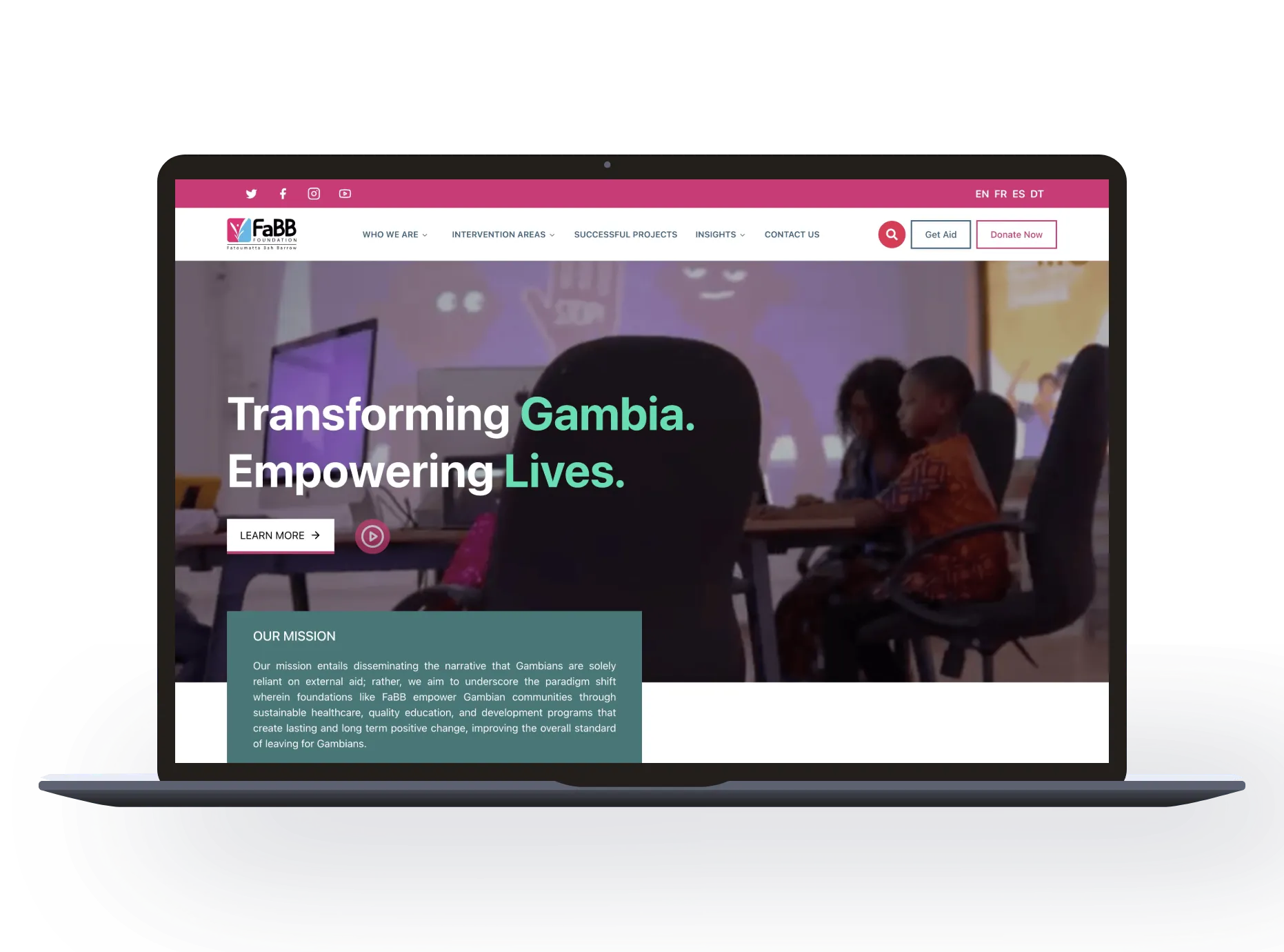 Laptop showing a charity website: Transforming Gambia. Empowering Lives.