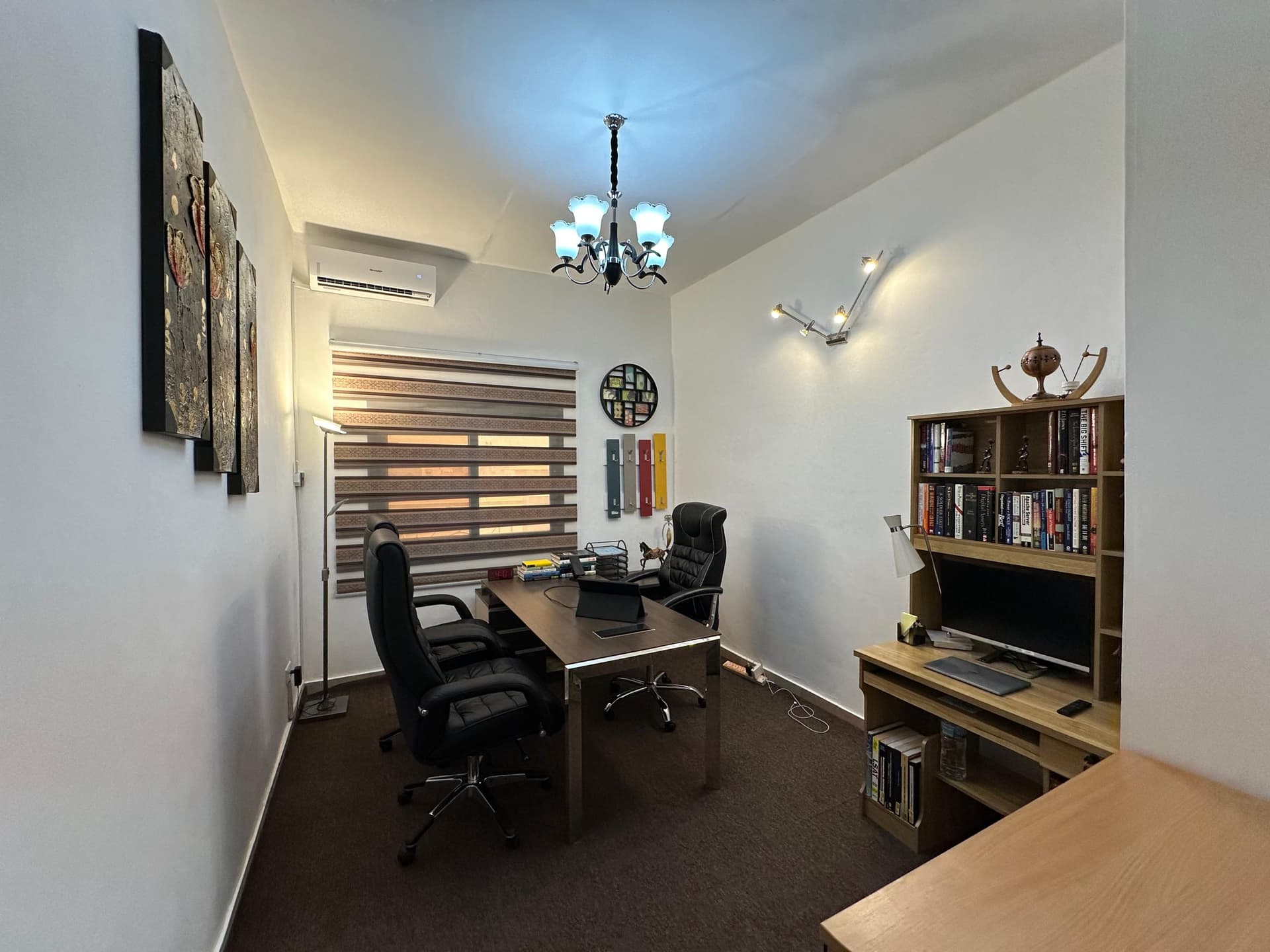 Private office with a desk, bookshelf and chandelier