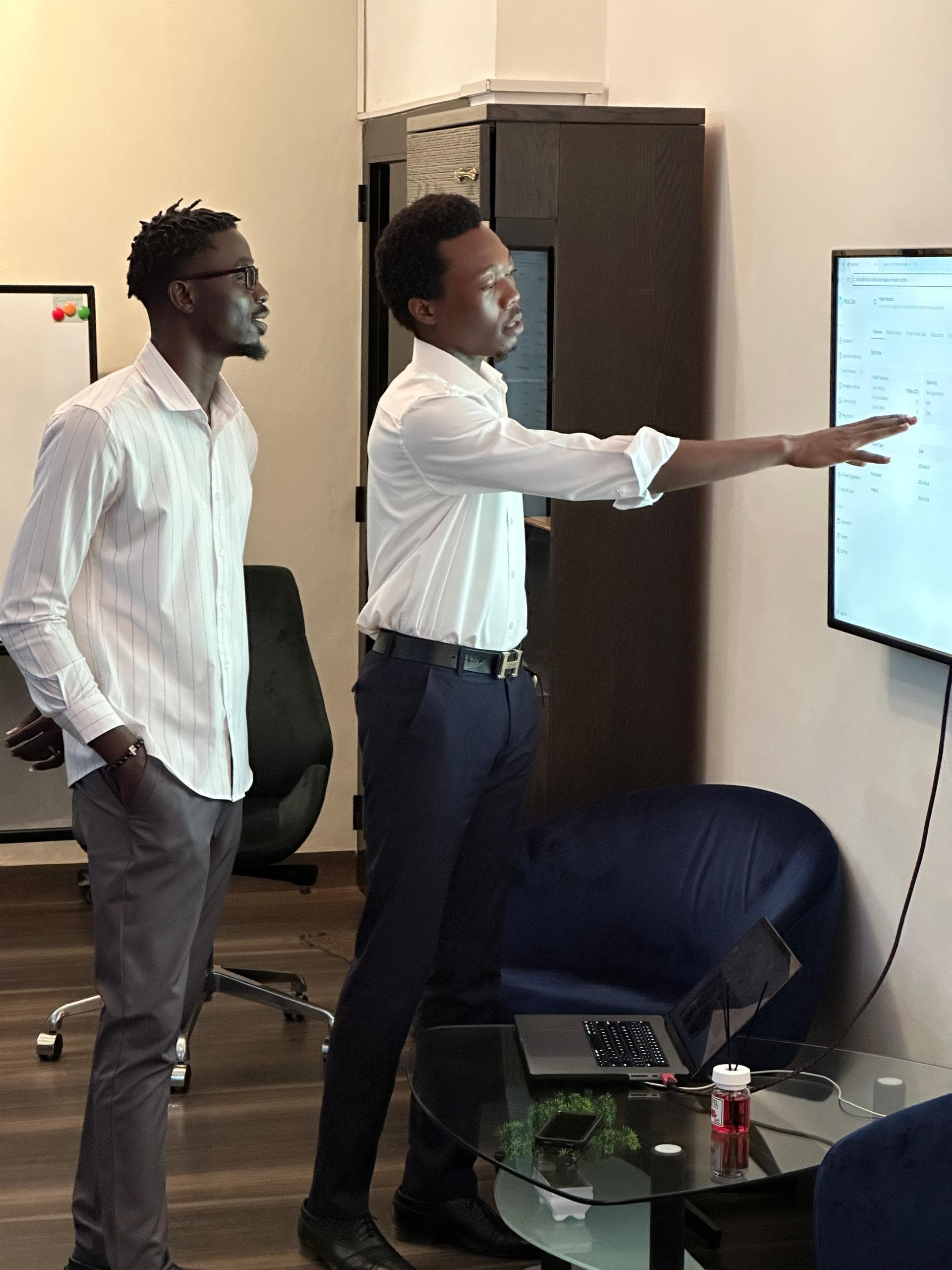 Two colleagues reviewing work on a wall-mounted screen