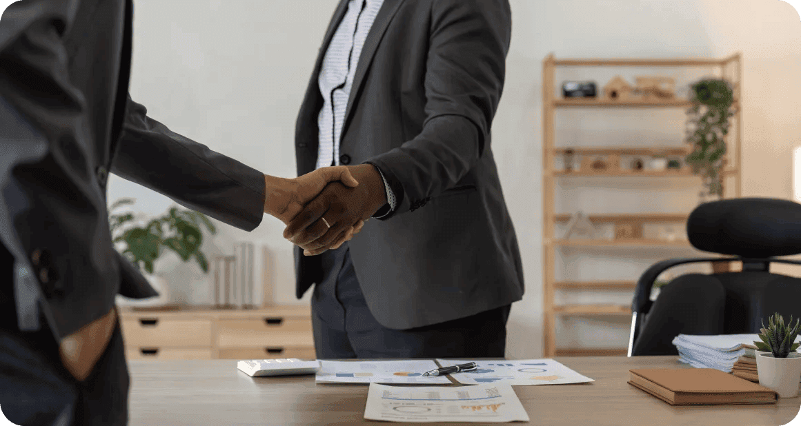 Two business people shaking hands across an office desk