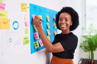 Scrum master smiling beside a sticky-note task board