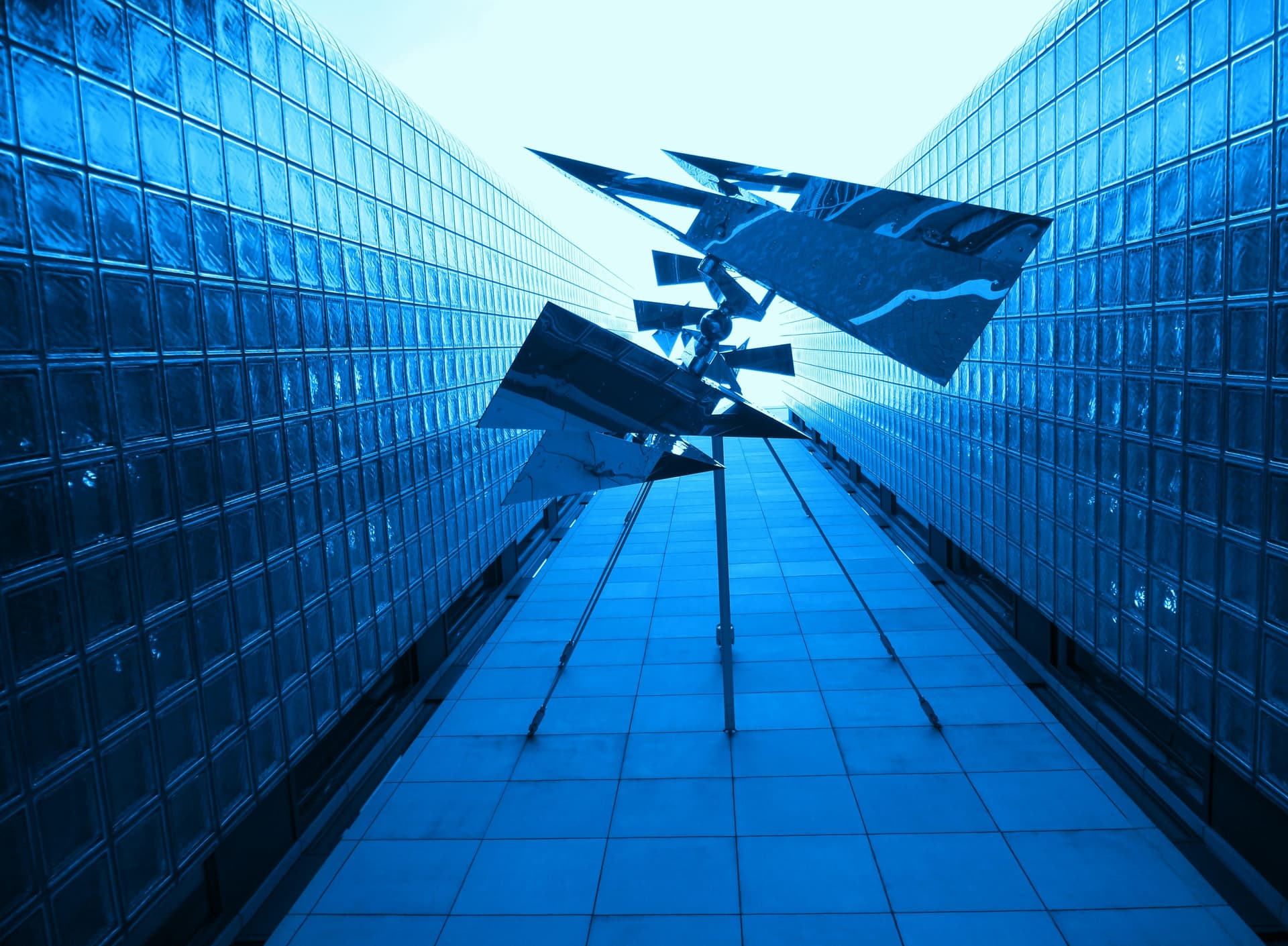 Looking up between glass office towers at a modern sculpture